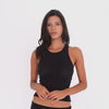 Model wearing and moving in the black Kimi Tank with matching black shorts, showing the tank’s fitted racerback silhouette and semi-sheer ribbed fabric **black
