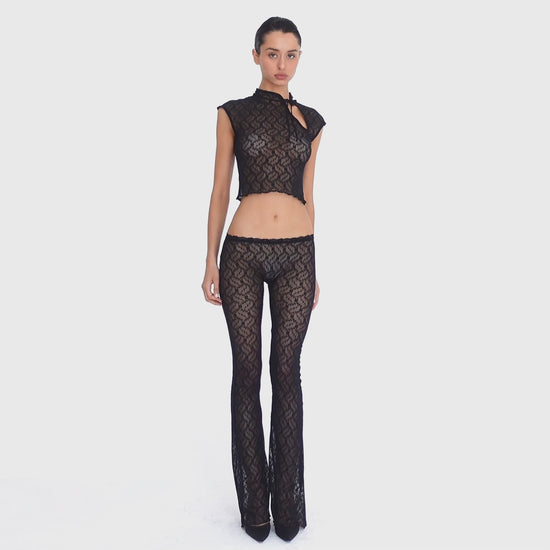 Video: Model turns and poses in the Liani Pant in Black, showing the sheer floral lace, low rise waistband and flared leg from multiple angles. **black