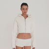 Video: Model wearing the ivory Sfera Jacket, showing the cropped fit, ribbed texture, oversized hood, silver zipper and back logo detail from multiple angles. **ivory