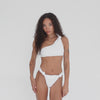 Video of model wearing the Are You Am I Aimi Bikini Bottom in white, walking and posing to display the high-cut, knotted hip design in plush terry fabric. **white