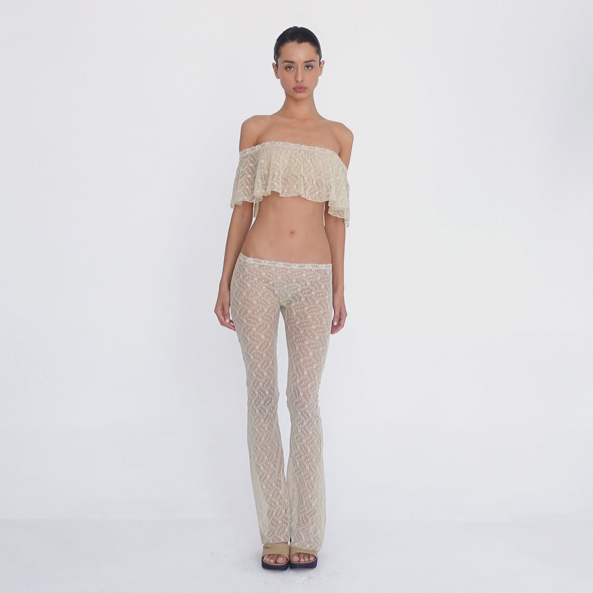 Video: Model turns and poses in the Liani Pant in Nude, showing the sheer floral lace, low rise waistband and flared silhouette from multiple angles. **nude