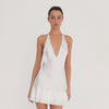 Video: Model turning to show the white Atalanta Dress from multiple angles, highlighting its plunging neckline, open back, halter ties and double ruffle hem **white
