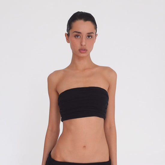 Video: Model turns and poses in the Meili Bandeau in Black, showing the cropped strapless fit, all-over ruching and fitted silhouette from multiple angles. **black