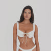 Video: Model wearing and moving in the ARE YOU AM I Nou Swim Top in Cream, featuring structured underwire cups, wide straps, and an adjustable front tie **cream