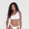 Model moves and poses in the Are You Am I Aimi Bikini Top in white terry, showcasing the one-shoulder knotted strap, elastic hem, and soft lounge-ready texture from multiple angles. **white