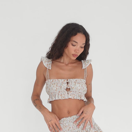 Model showcasing the Are You Am I Eran Top in floral, a smocked ruffle crop top with button front closures and frill straps, styled with the matching Eran Skirt, shown from multiple angles. **floral