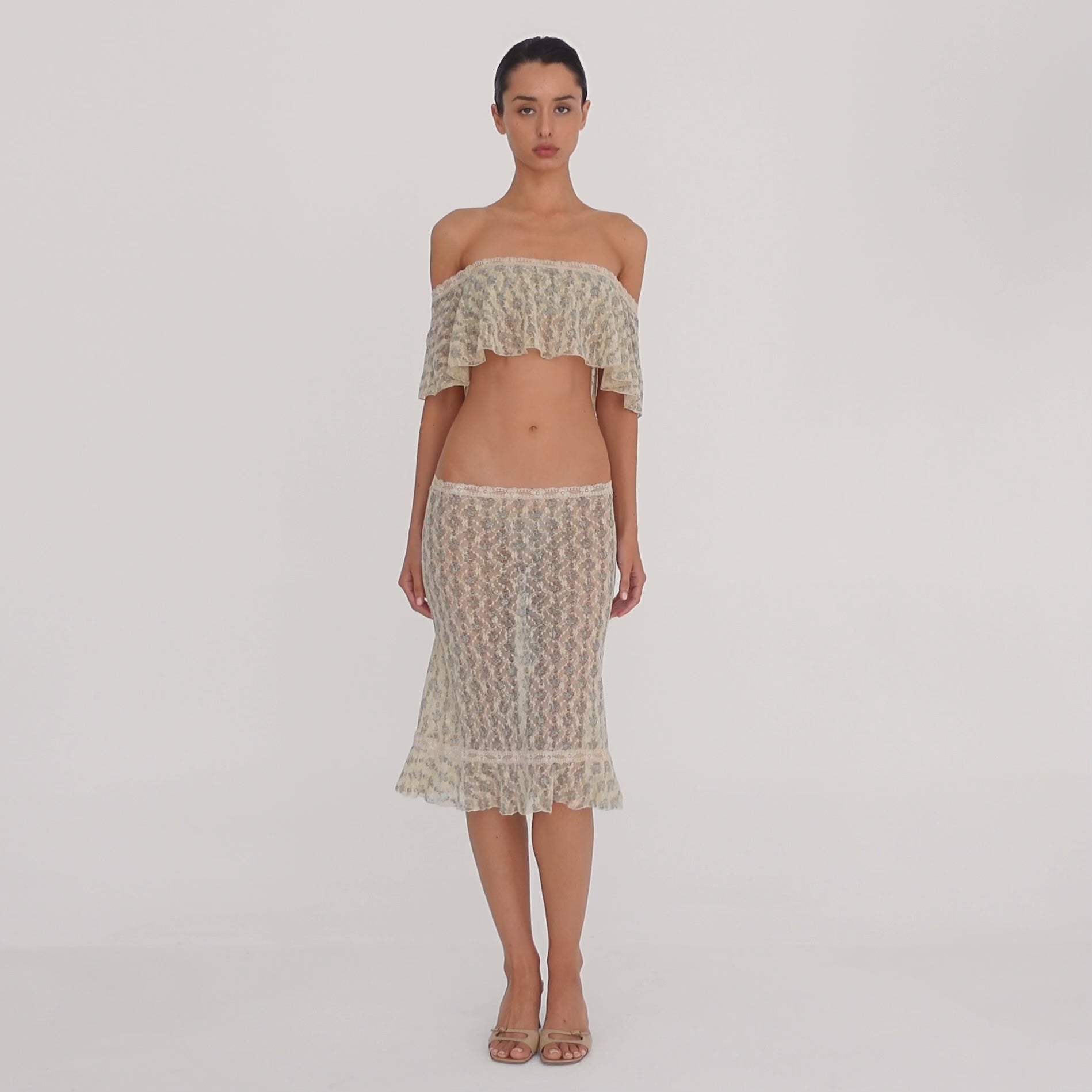 Video: Model wearing the Liulu skirt, a sheer cream floral lace midi skirt with a low-rise waist, lace trim, and ruffled hem, styled with the matching off-the-shoulder top. **sky blossom