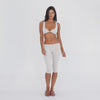 Detail: Close-up of the sand Clio Capri at the hip, highlighting the ribbed fabric, wide fold-over waistband, seam construction, and lace-up side detail **sand