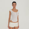 Video: Model wearing the ivory Nimue Short, showing the low-rise micro fit, soft ribbed texture, short hemline and tonal ARE YOU AM I embroidery from multiple angles. **ivory