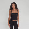 Model walking and posing in the Illi Tank in black, showing the stretchy ribbed texture and flattering silhouette from all angles. **black