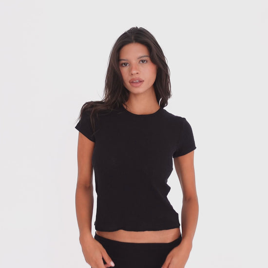 Model wearing and moving in the Kimi Tee in Black, a fitted short-sleeve tee with a crew neckline and slightly cropped silhouette **black