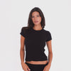 Model wearing and moving in the Kimi Tee in Black, a fitted short-sleeve tee with a crew neckline and slightly cropped silhouette **black