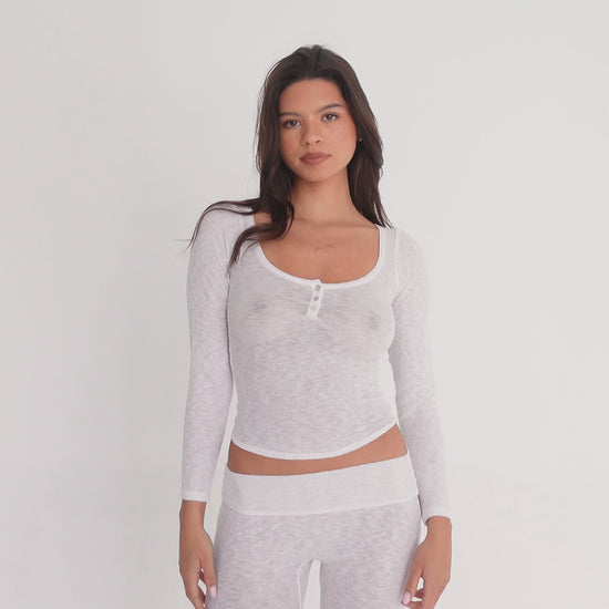 Model modeling a sheer white long sleeve scoop neck henley top with three buttons, shown from front, side, and back angles while posing. **white