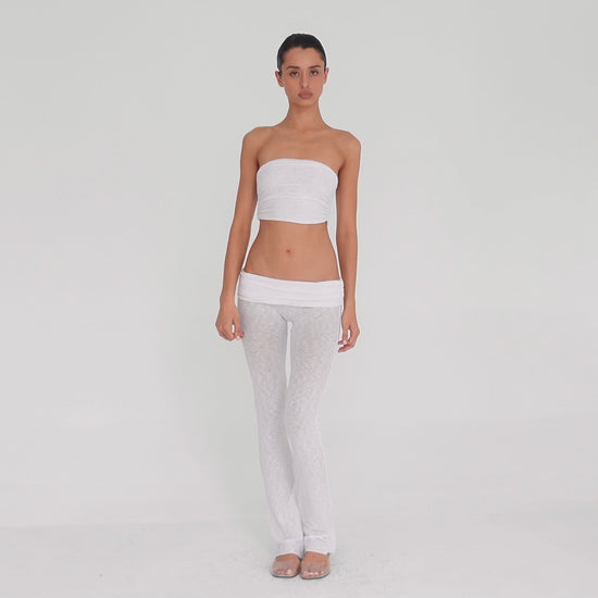 Video: Model turns and poses in the Meili Pant in White, showing the low rise fit, wide ruched fold-over waistband, sheer fabric and subtly flared leg. **white