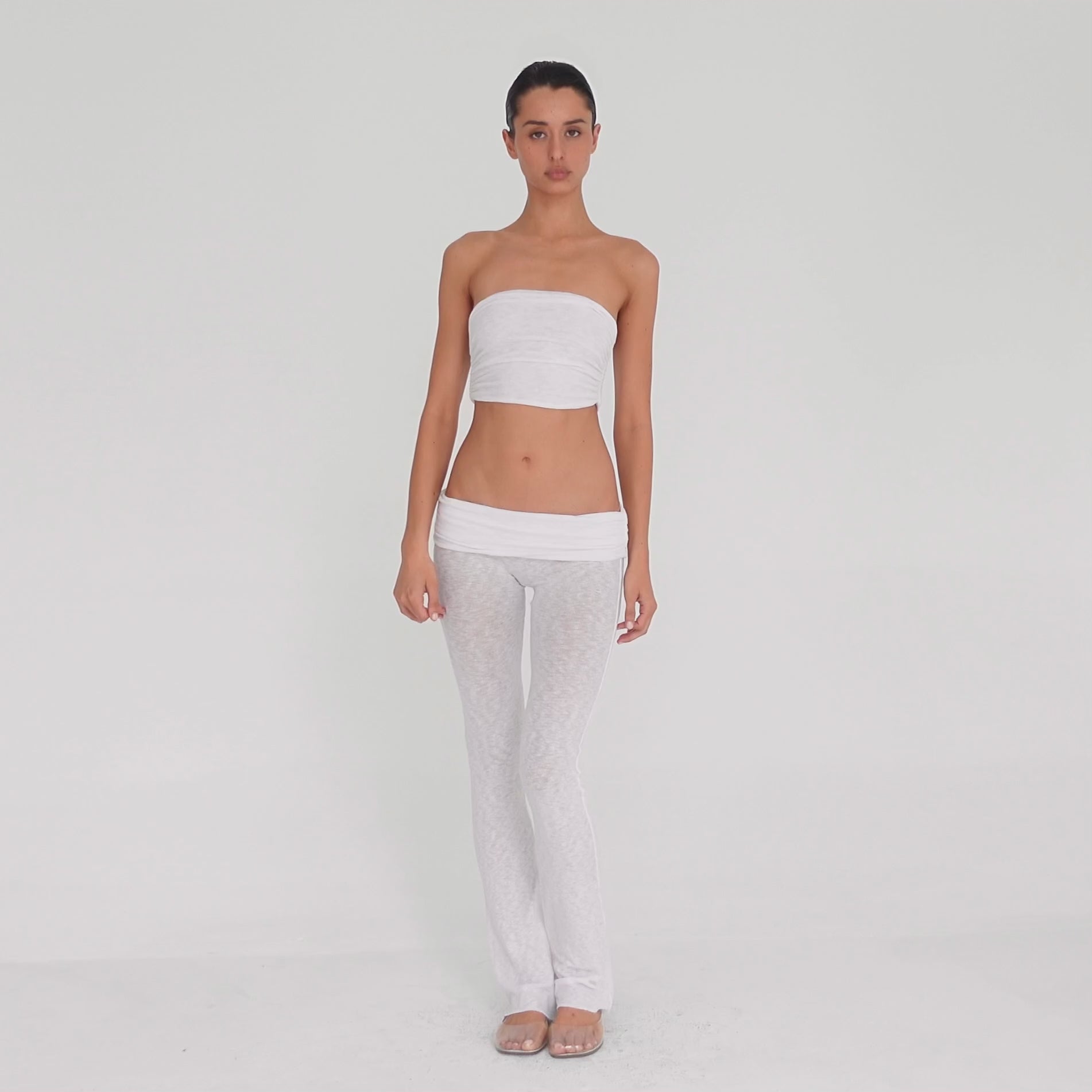 Video: Model turns and poses in the Meili Pant in White, showing the low rise fit, wide ruched fold-over waistband, sheer fabric and subtly flared leg. **white